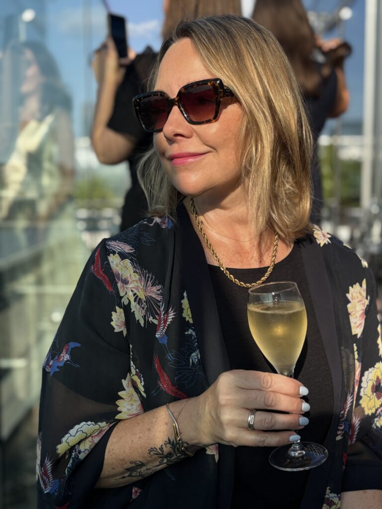 Blonde woman wearing sunglasses with glass of Champagne